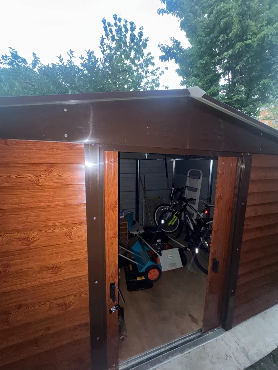 Professional gardening equipment — mower and tools stored ready in a secure garden shed