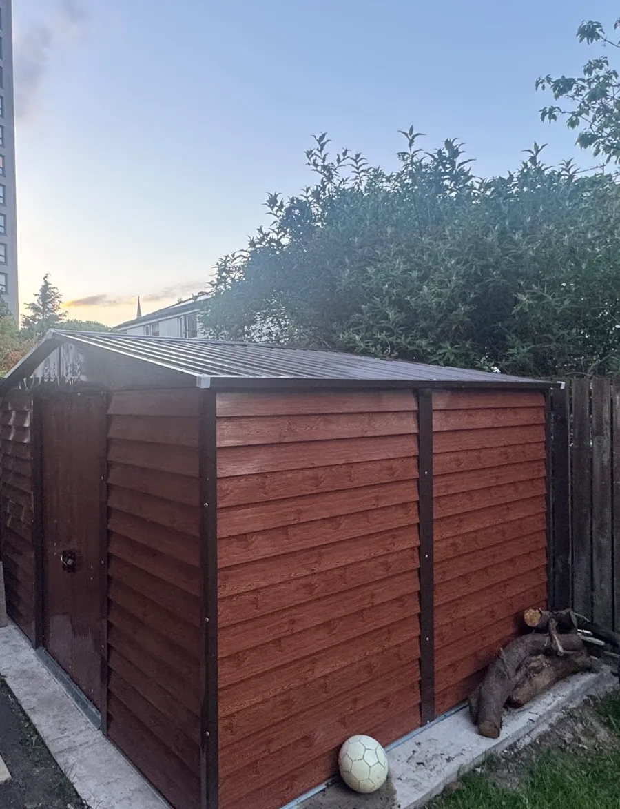 A tidy garden with a clean, secure storage shed installed in a Manchester back garden at dusk